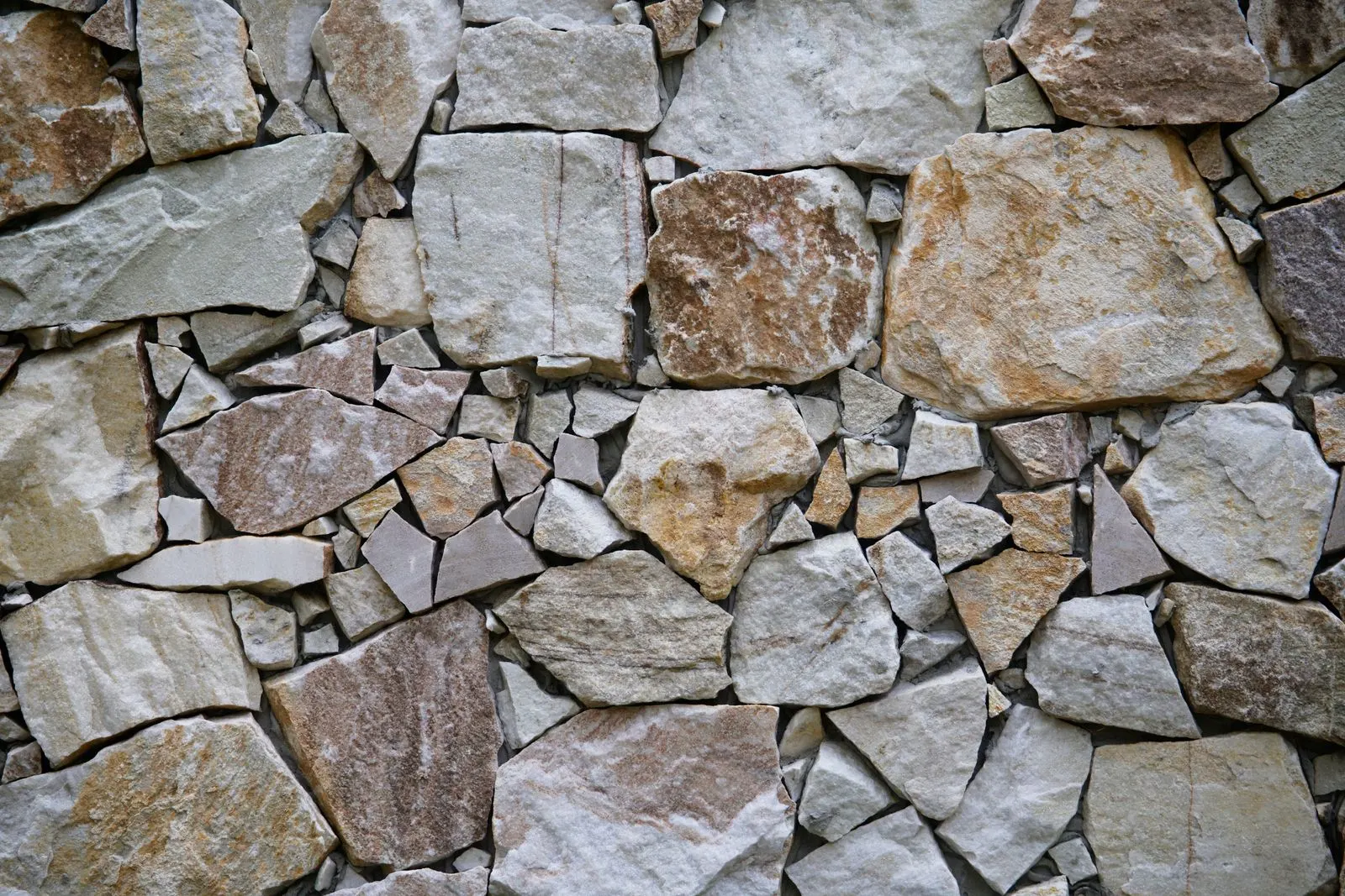 Natural stone wall with irregular beige and grey patterns